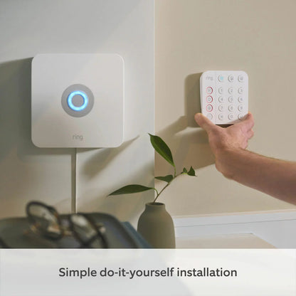 Ring 15 Piece Alarm 2nd Gen Starter Kit in sleek white showing the base station, keypad, outdoor siren, indoor camera, battery video doorbell, sensors, and motion detectors arranged neatly on a modern light backdrop.