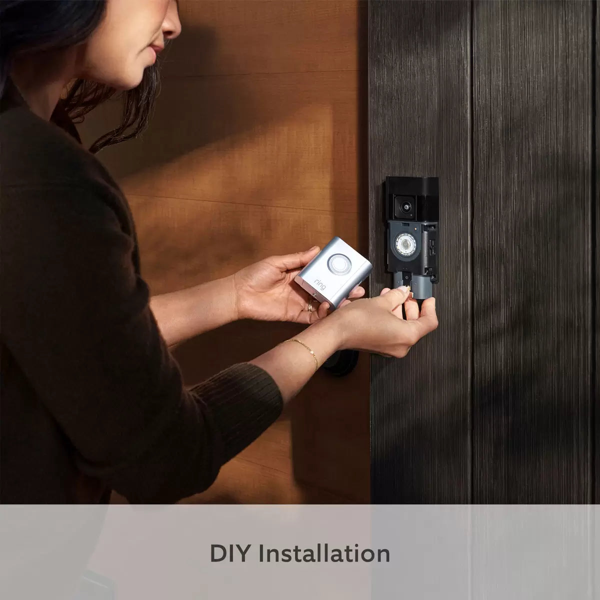 A satin nickel Ring Battery Video Doorbell Pro mounted next to a wooden front door, showing the wide lens perspective, beside a compact white Chime plugged into a hallway socket.