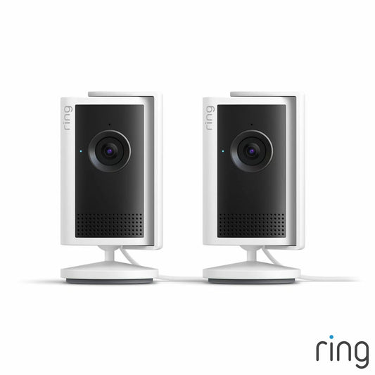 Pair of white Ring Plug-In Indoor Camera Plus units standing side by side on adjustable swivel mounts against a bright modern home interior.
