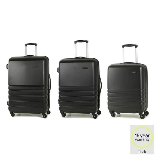 Front angle view of the black Rock Byron 3 piece hardside luggage set lined up on a modern airport lounge floor featuring cabin, medium, and large suitcases.
