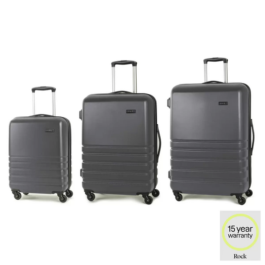 Rock Byron 3 piece hardside luggage set in charcoal standing together in size order on a modern minimalist airport floor.