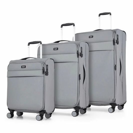 Front angle view of the Rock Harper 3 piece softside luggage set in charcoal grey showing nested cabin, medium, and large expandable suitcases on a modern airport lounge floor.