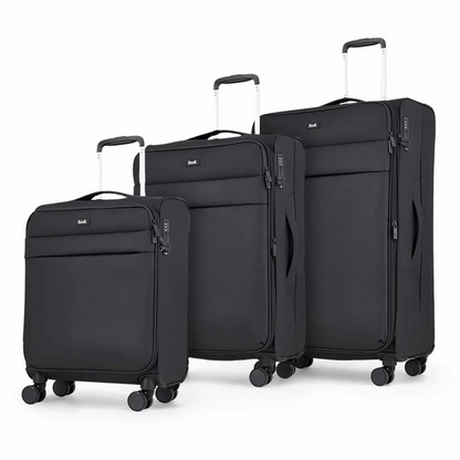 Front angle view of the Rock Harper 3 piece softside luggage set in charcoal grey showing nested cabin, medium, and large expandable suitcases on a modern airport lounge floor.
