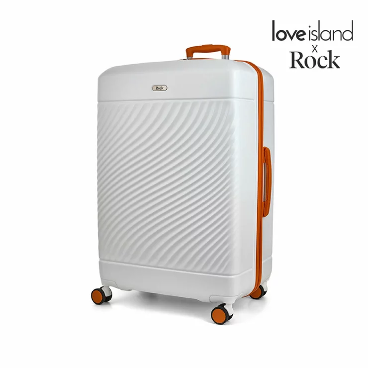 Front angle shot of the vibrant Rock Love Island hardside cabin suitcase standing upright on four double spinner wheels inside a modern airport terminal.
