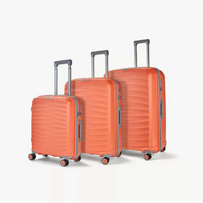 Three-quarter angle of three ocean-blue Rock Sunwave hardside suitcases stacked in cabin, medium, and large sizes on a glossy terminal floor.