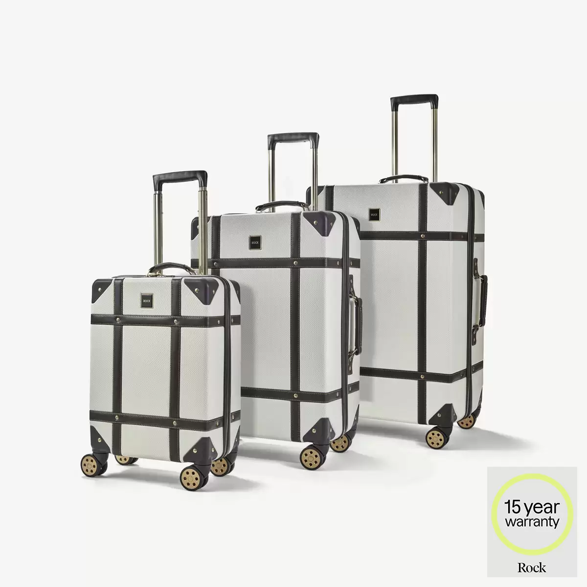 Front three-quarter view of the three-piece Rock Vintage hardside luggage set in three sizes standing on airport tile.