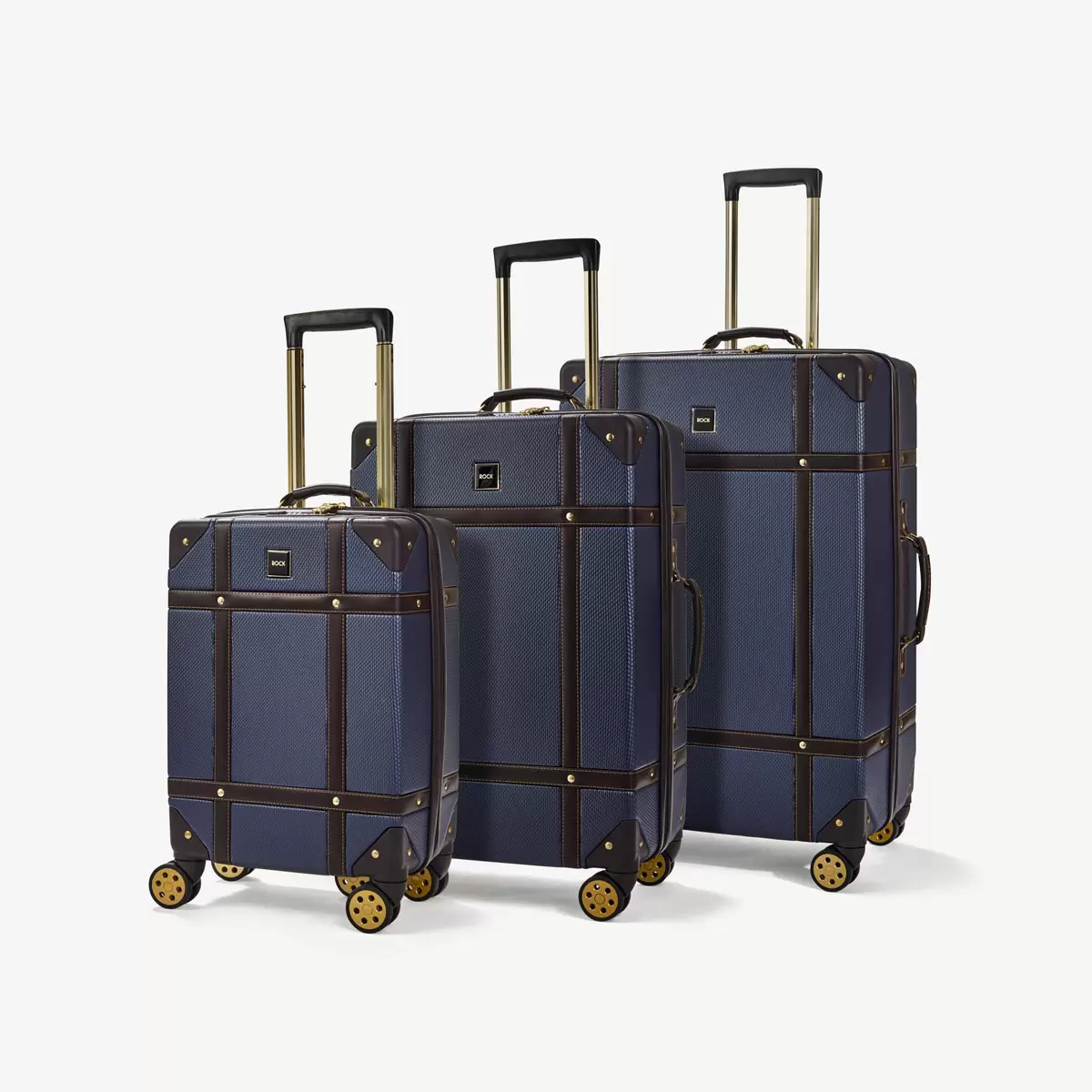 Front three-quarter view of the three-piece Rock Vintage hardside luggage set in three sizes standing on airport tile.