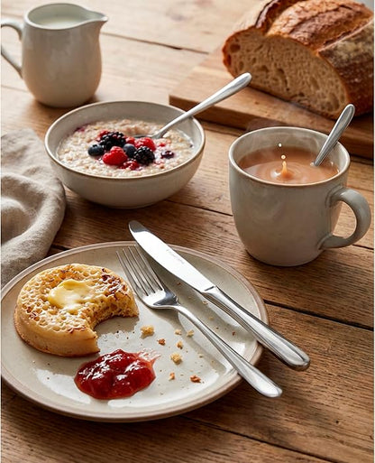 Four-person set of shiny silver Russell Hobbs Capri 18/10 stainless steel cutlery arranged neatly on a dark wooden dining table.