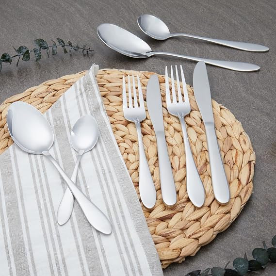Top-down view of the 44-piece silver polished Russell Hobbs Lisbon stainless steel cutlery set arranged neatly on a dark wooden dining table setting.