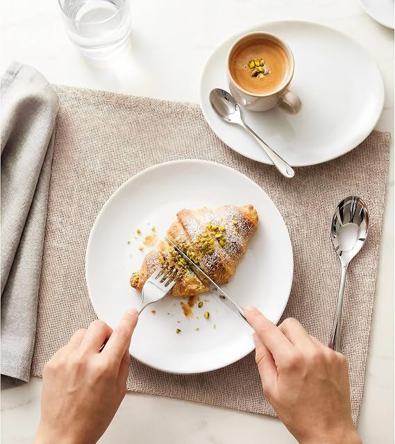 Front view of the 16-piece silver Russell Hobbs London stainless steel cutlery set arranged neatly on a wooden dining table.
