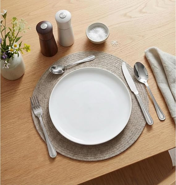 Top-down view of the silver polished Russell Hobbs Prague 24-piece cutlery set neatly arranged on a modern wooden dining table setting.