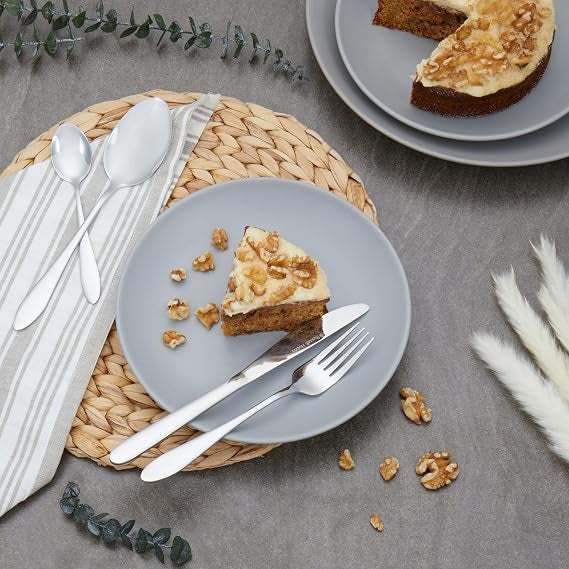 Top-down view of the silver polished Russell Hobbs Prague 24-piece cutlery set neatly arranged on a modern wooden dining table setting.