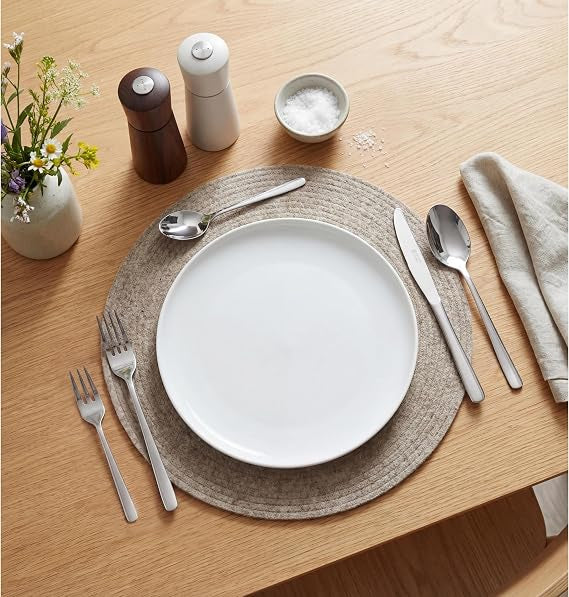 Russell Hobbs Vienna 60-piece silver mirror-polished stainless steel cutlery set arranged neatly on a dining table including knives, forks, and spoons.