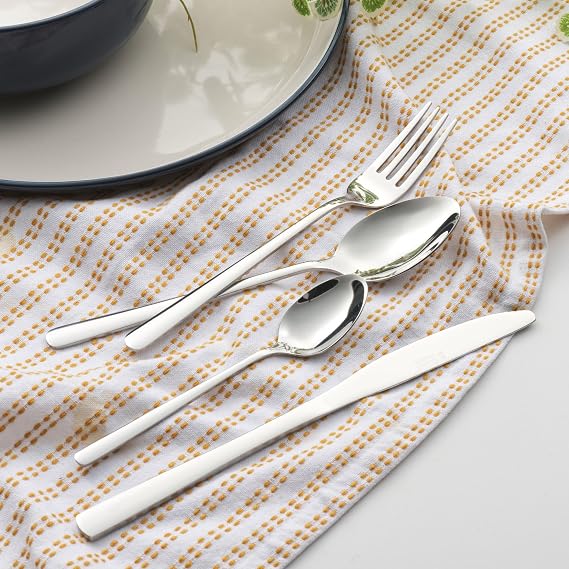 Top-down view of the 16-piece Russell Hobbs Vienna stainless steel cutlery set arranged neatly on a dark wooden dining table showcasing its mirror-polished reflective finish.