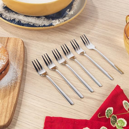 Six pack of silver polished 18/0 stainless steel Russell Hobbs Vienna dessert forks arranged neatly on a dark wooden dining table.