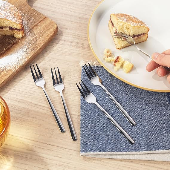 Six pack of silver polished 18/0 stainless steel Russell Hobbs Vienna dessert forks arranged neatly on a dark wooden dining table.