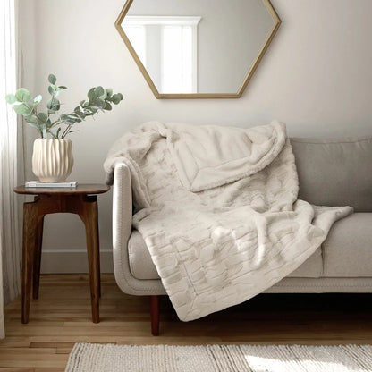Soft cream Safdie luxury faux rabbit fur throw folded neatly on a grey linen sofa showing off its plush brushed texture.