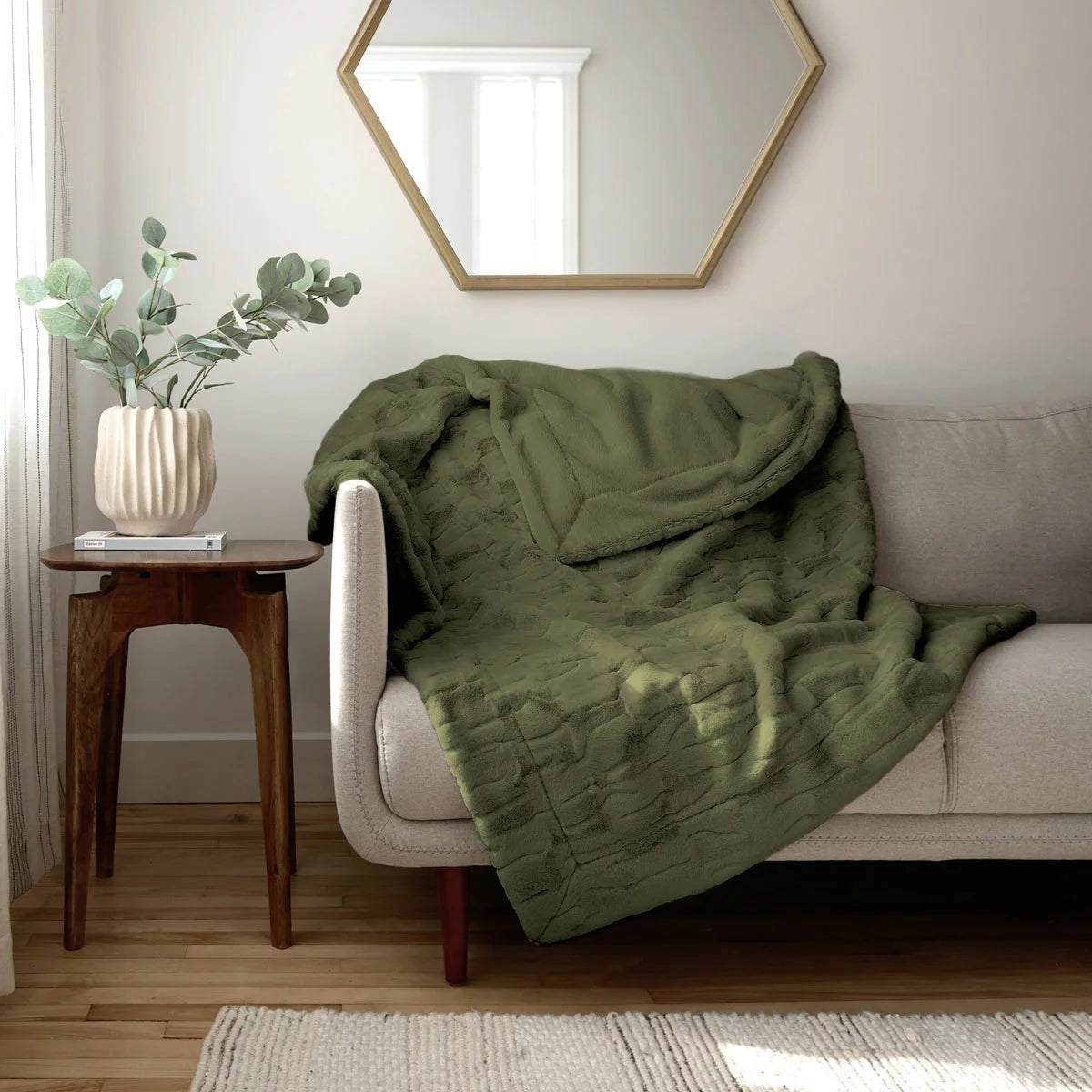 Soft cream Safdie luxury faux rabbit fur throw folded neatly on a grey linen sofa showing off its plush brushed texture.