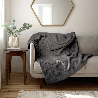 Soft cream Safdie luxury faux rabbit fur throw folded neatly on a grey linen sofa showing off its plush brushed texture.