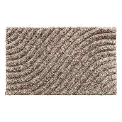 Overhead angled view of the plush grey Safdie Tufted Wave Bath Mat showing its sculpted high-low wave pattern on a light tiled bathroom floor.