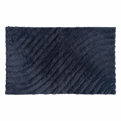 Overhead angled view of the plush grey Safdie Tufted Wave Bath Mat showing its sculpted high-low wave pattern on a light tiled bathroom floor.