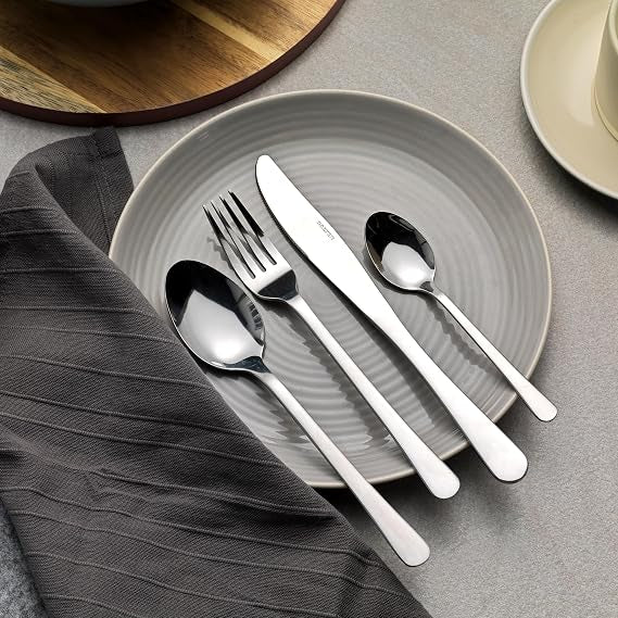 Overhead view of the silver Salter Bakewell 48-piece stainless steel cutlery set arranged neatly on a dark wooden table setting.