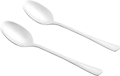 Four-piece Salter Buxton mirror polish stainless steel serving spoon set arranged on a dark wooden dining table next to a salad bowl.