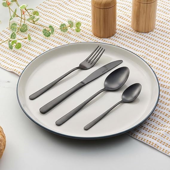 Overhead view of the 16-piece Salter Chiltern cutlery set in brushed matte black stainless steel arranged neatly on a dark slate dining table.