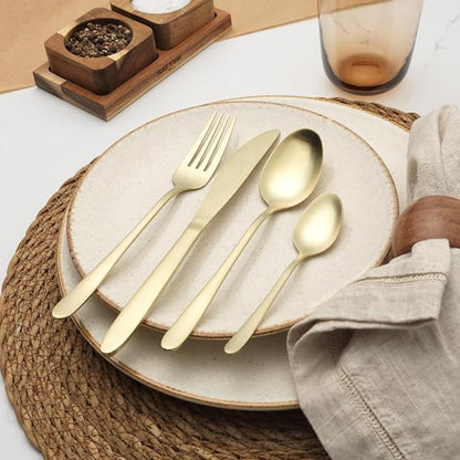 Salter Chiltern 16-piece brushed gold stainless steel cutlery set arranged on a modern dark wood dining table setup.
