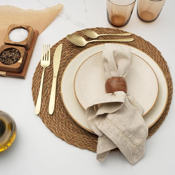 Close-up of Salter Chiltern 32-piece brushed gold stainless steel cutlery set arranged neatly on a dark slate dining table.