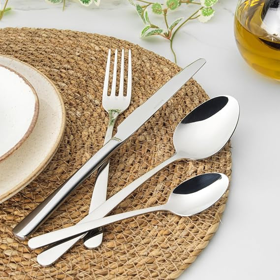 Salter Harrogate Kendal 16 piece mirror polished 18/10 stainless steel cutlery set neatly arranged on a wooden dining table.