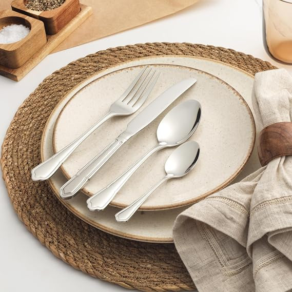 Salter Richmond 24 piece silver stainless steel cutlery set neatly arranged on a dark wooden dining table showcasing polished knives, forks, and spoons.