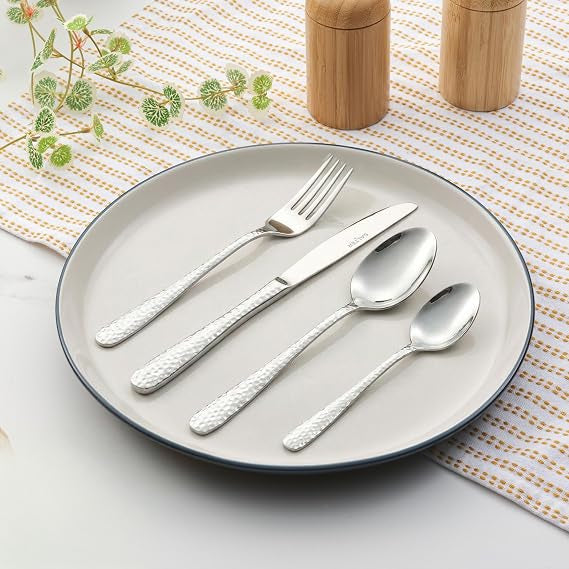 Top-down view of the 16-piece silver Salter Soho cutlery set arranged neatly on a grey linen tablecloth featuring polished knives, forks, tablespoons, and teaspoons.