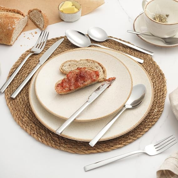 Silver Salter Winslow 44-piece polished stainless steel cutlery set arranged neatly on a dark wooden dining table setting.