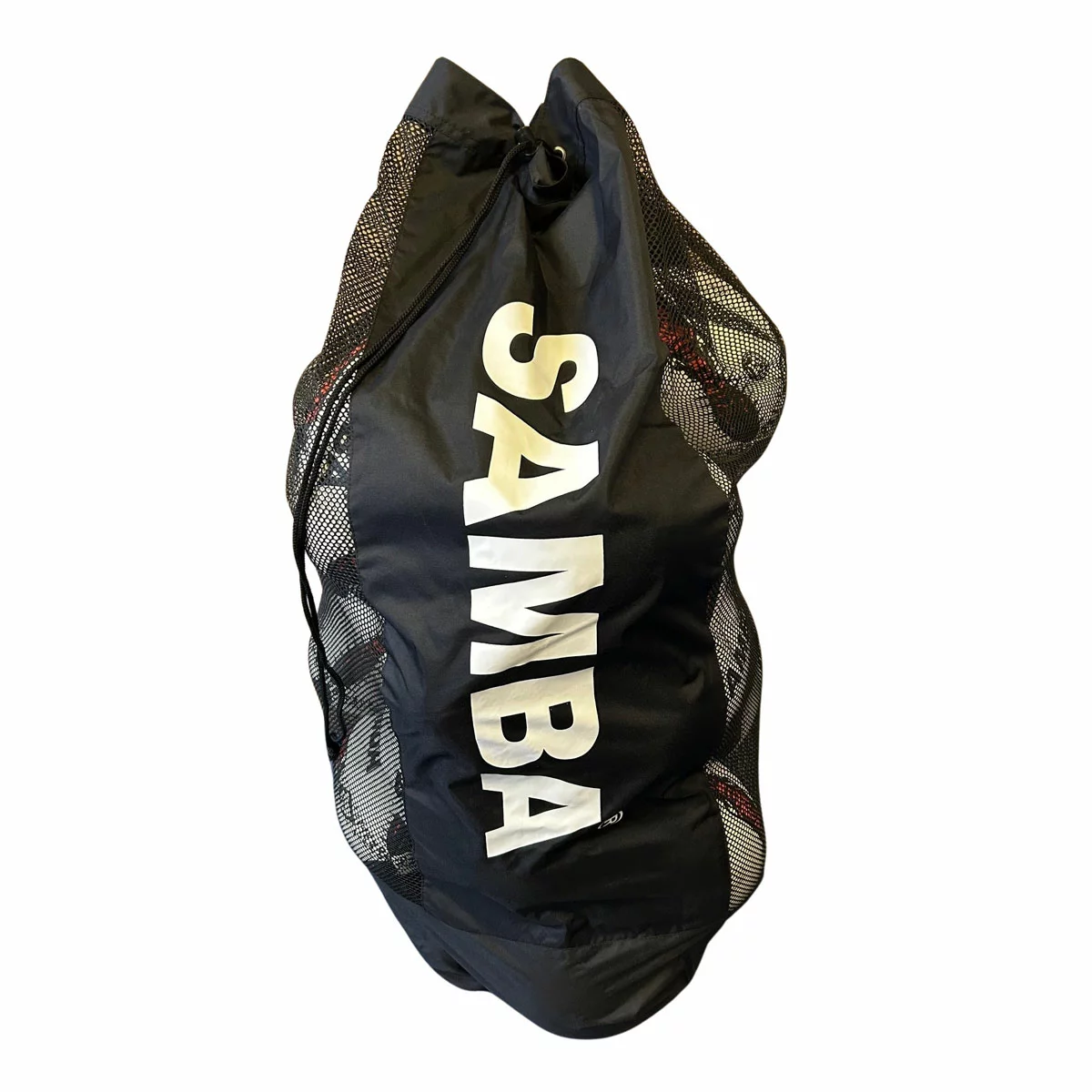 Large black mesh carry bag packed with 20 white and blue hand-stitched Samba Racer rugby training balls sitting on a muddy grass rugby pitch.