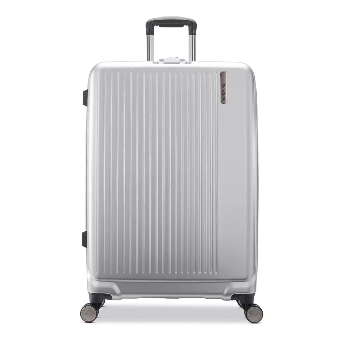 Samsonite Amplitude large hardside case in metallic finish standing upright in a sleek airport terminal corridor.