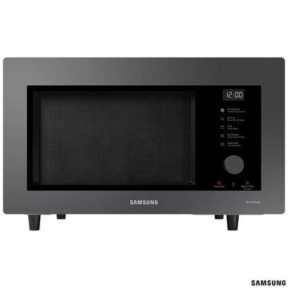 Black Samsung 32L smart microwave oven with glass door and digital control panel sitting on a contemporary kitchen countertop beside cooked food.