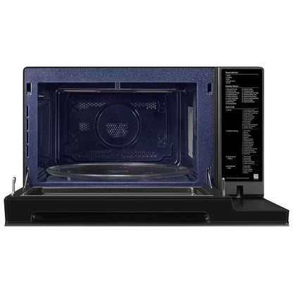 Black Samsung 32L smart microwave oven with glass door and digital control panel sitting on a contemporary kitchen countertop beside cooked food.
