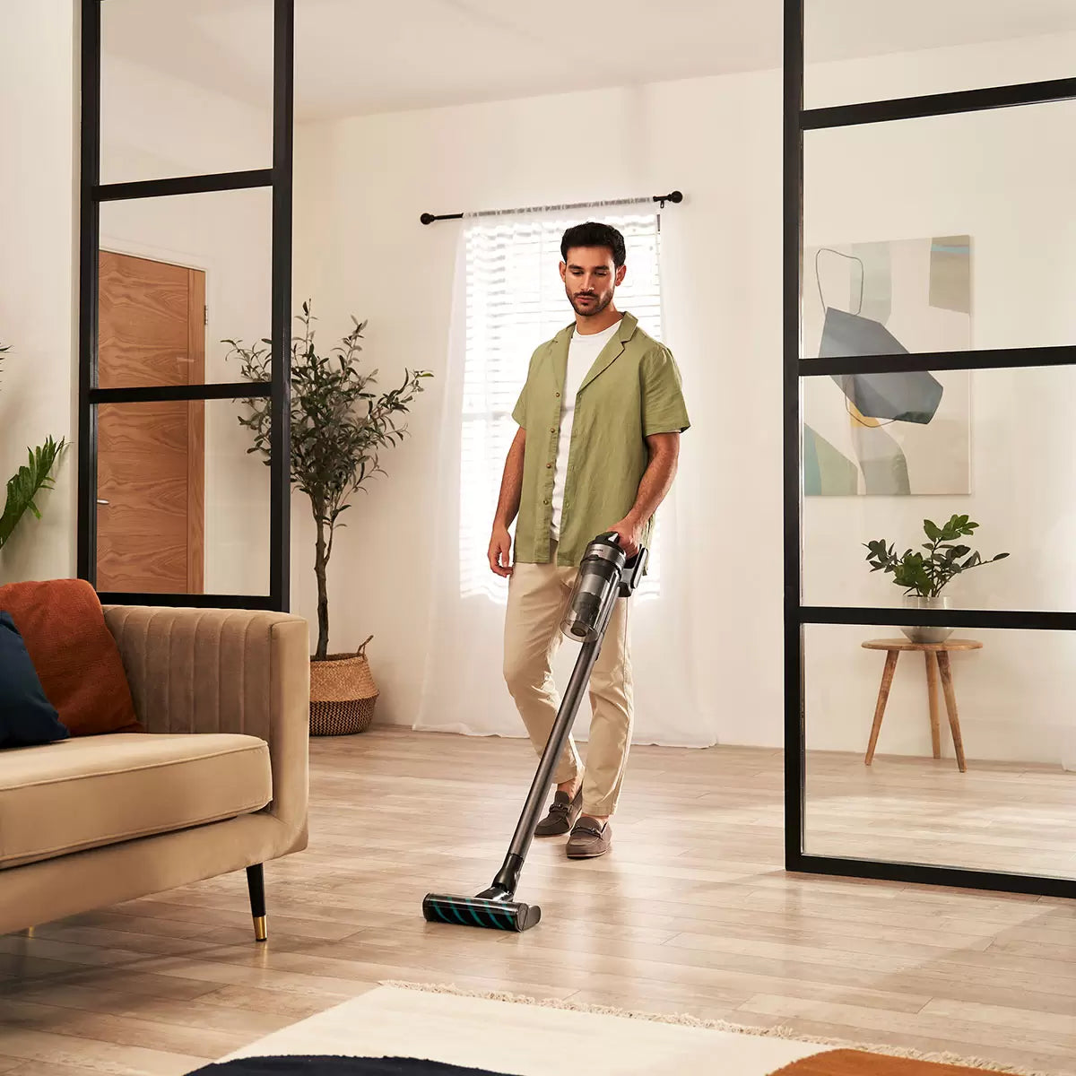 Front view of the silver and silver-grey Samsung Jet 75E Complete cordless stick vacuum cleaner standing upright on its 2-in-1 wall dock against a modern white wall.