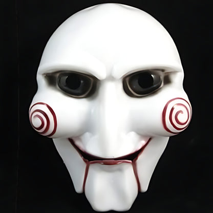 Front view of a white Saw Billy puppet horror mask with red spiral cheek details and red lips on a black background.