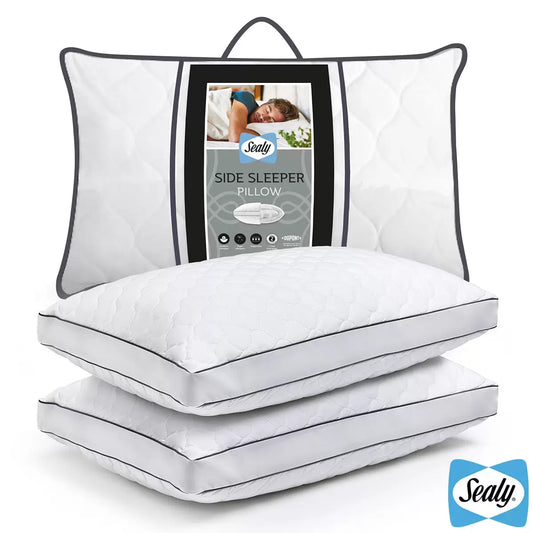 Pair of white Sealy Side Sleeper Pillows featuring a cushioned cotton finish arranged neatly on a bed.