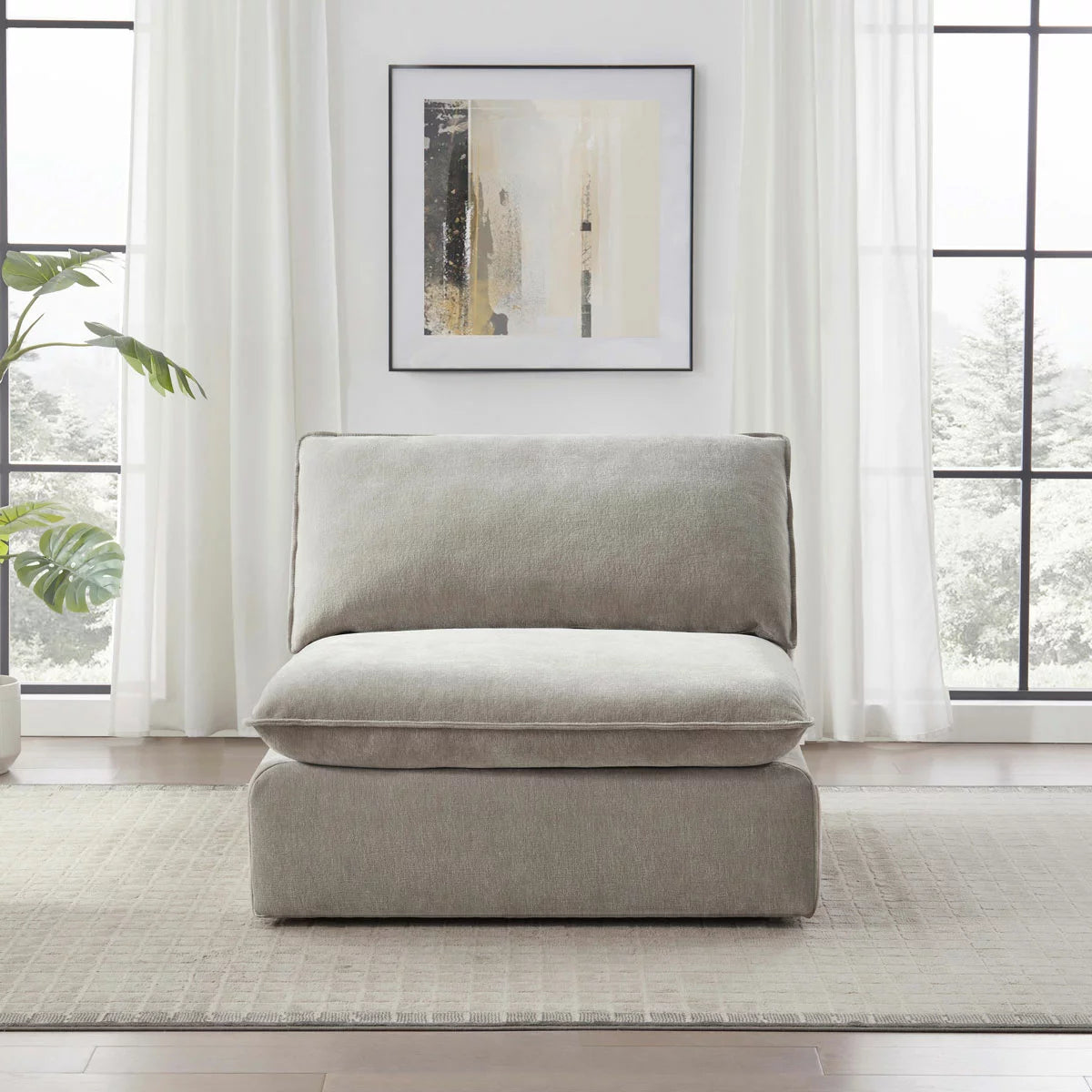 Front view of the Sereen beige fabric armless chair with plush feather-blend cushions, positioned in a brightly lit, minimalist living room with wooden floors.