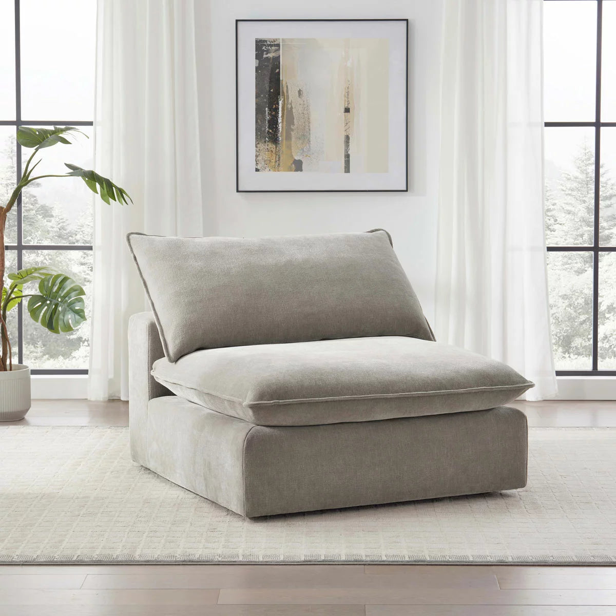 Front view of the Sereen beige fabric armless chair with plush feather-blend cushions, positioned in a brightly lit, minimalist living room with wooden floors.