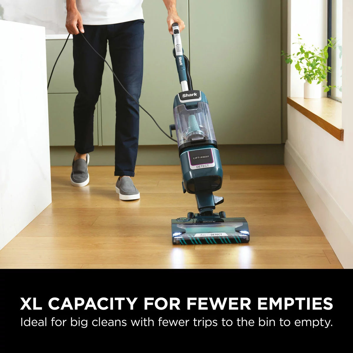 Front view of the navy and silver Shark Detect XL Pet Pro upright vacuum cleaner standing on a clean hardwood floor in a modern living room setting.