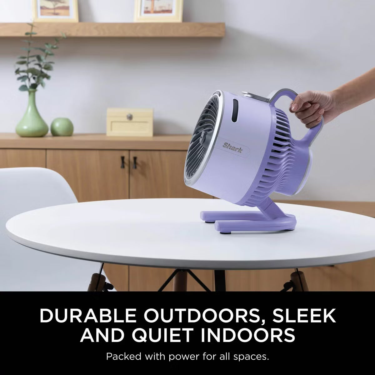 Front three-quarter view of the compact lilac Shark FlexBreeze HydroGo misting fan sitting on a garden table blowing a fine cooling mist.