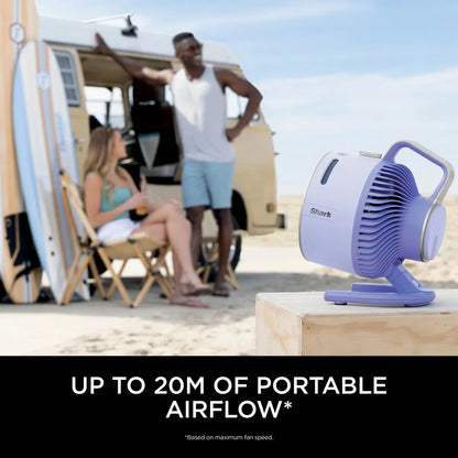 Front three-quarter view of the compact lilac Shark FlexBreeze HydroGo misting fan sitting on a garden table blowing a fine cooling mist.