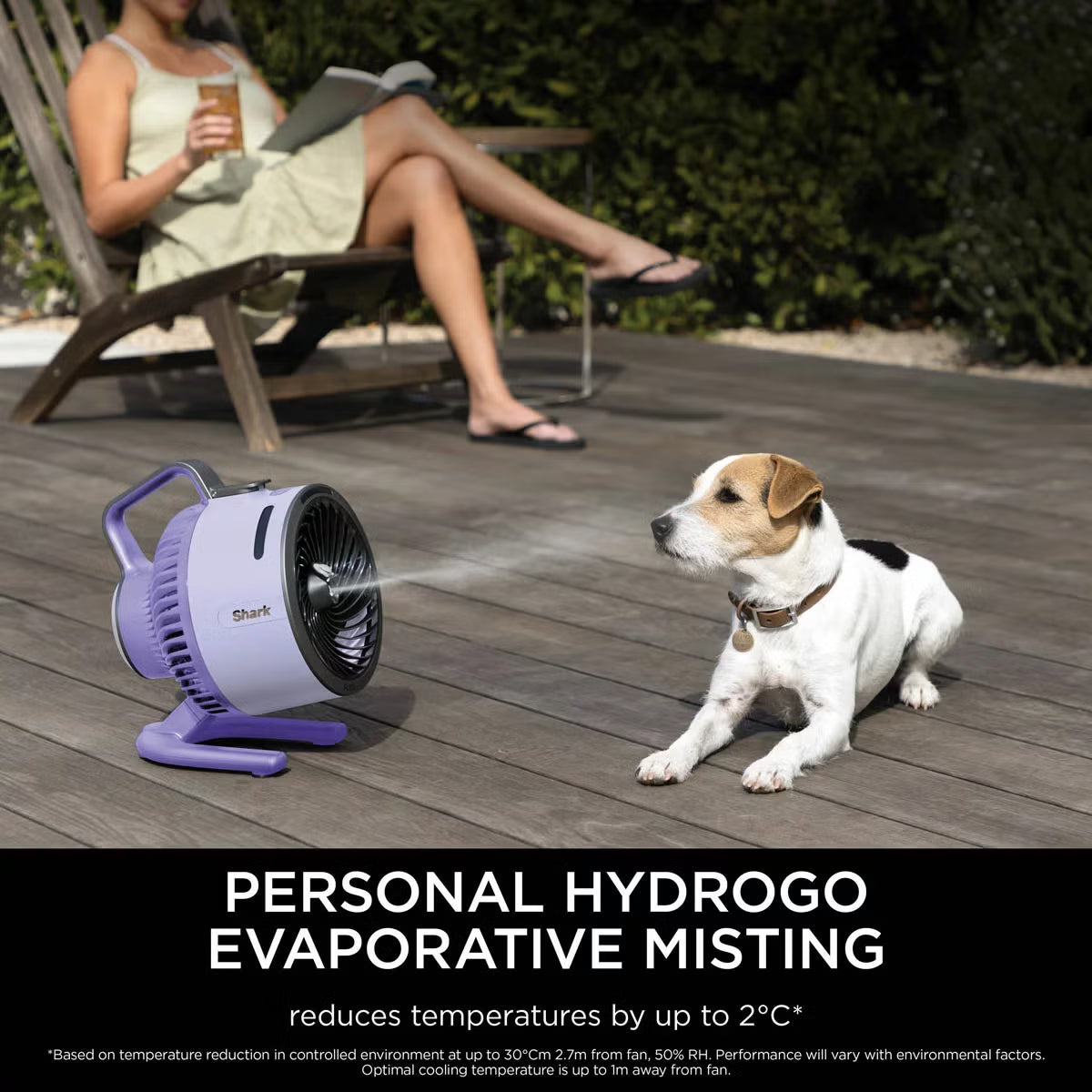Front three-quarter view of the compact lilac Shark FlexBreeze HydroGo misting fan sitting on a garden table blowing a fine cooling mist.
