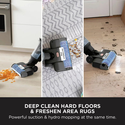 Front angle view of the slim metallic Shark HydroVac WD210UK cordless cleaner standing upright on its dark dock against clean kitchen tile flooring.
