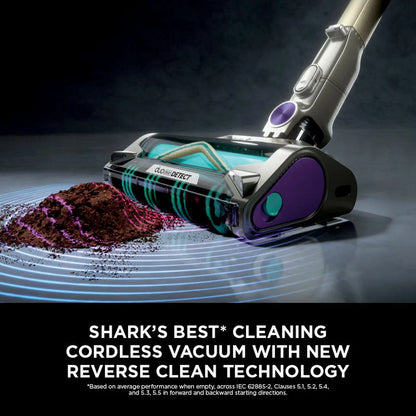 Front view of the dark teal Shark PowerDetect IP3251UKT cordless vacuum cleaner docked on its upright auto-empty charging base in a modern living room setting.