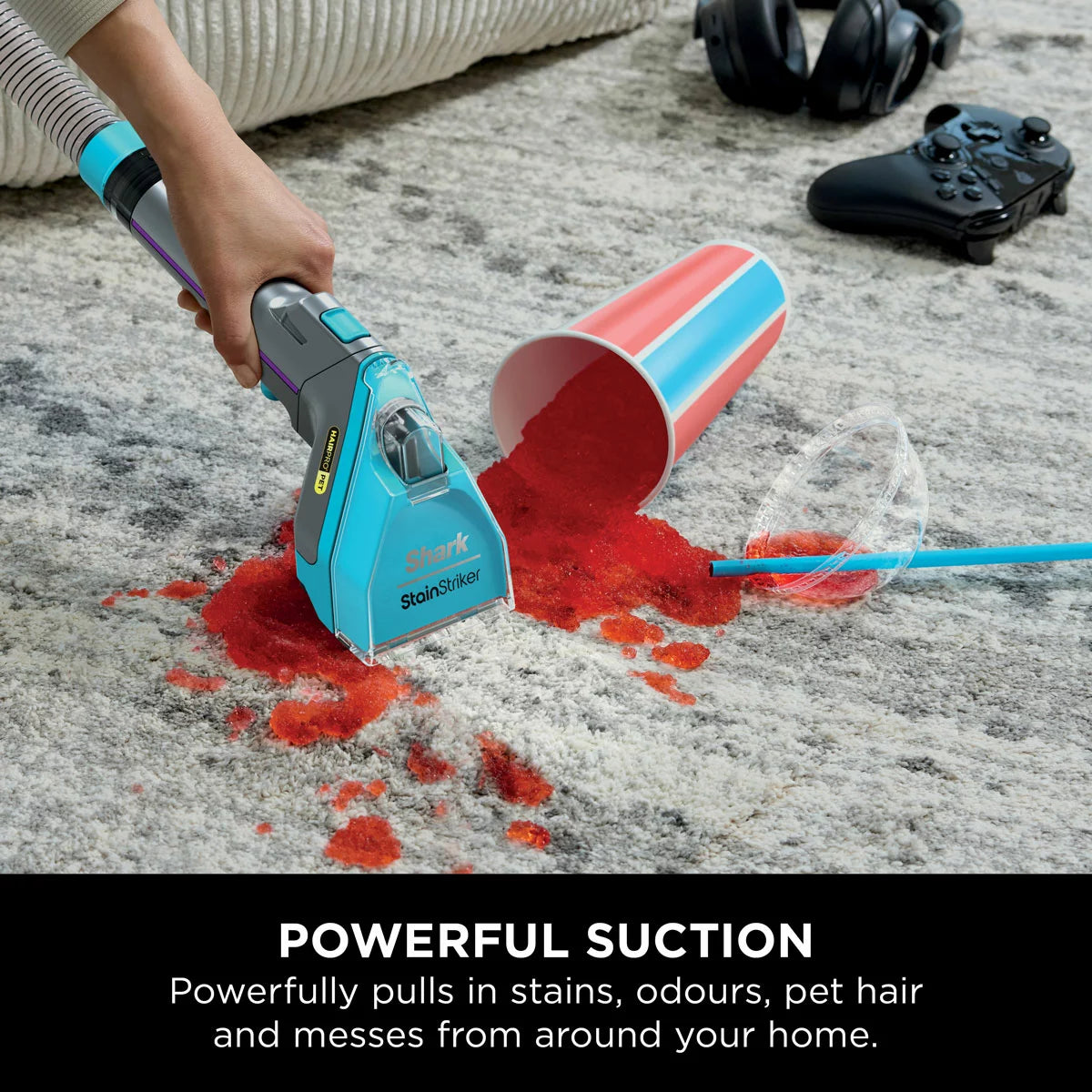 Front view of the white and deep navy Shark StainStriker HairPro PX250UKT spot cleaner sitting on a beige living room rug beside its attached hose and pet hair extraction tool.